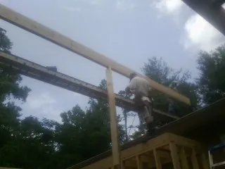 Carpenter setting a ridge beam over a new addition frame — Ice Dam Removal by Roofing Brothers in Platte Center