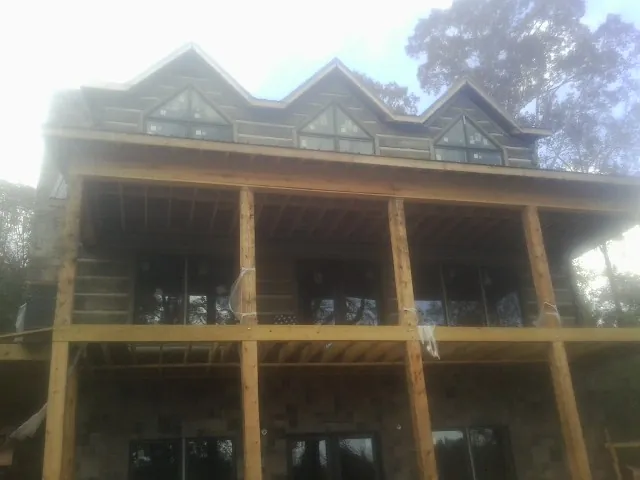 Dormers and porch framing on a large log home under construction — Roof Coating work by our crew in Platte Center