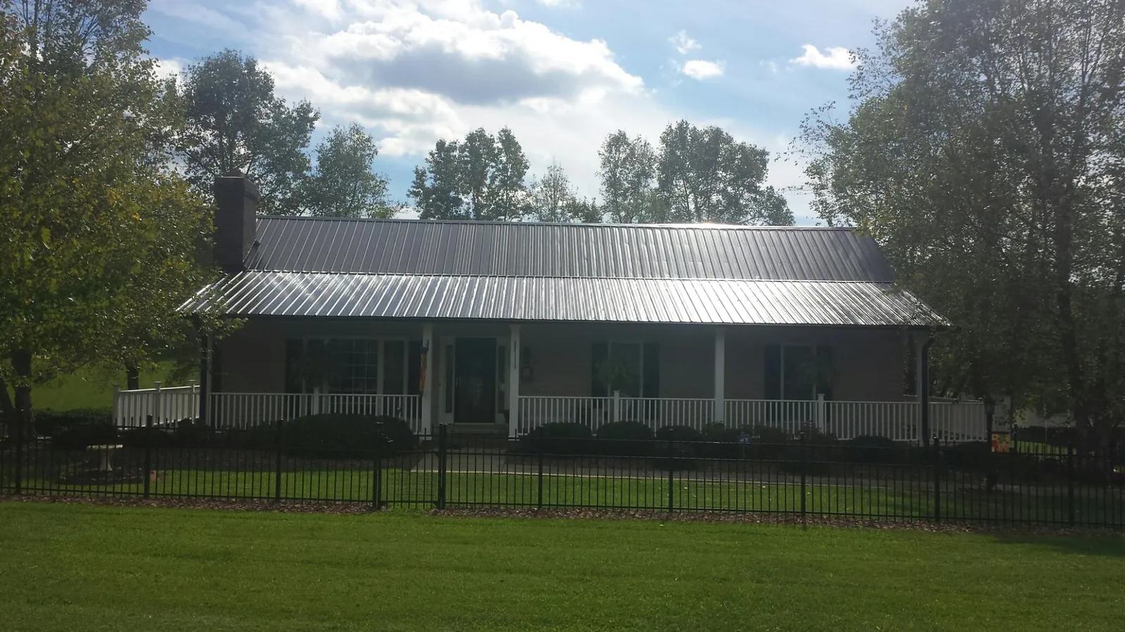 Gray metal roof on a brick ranch with a full width front porch — Gutter Guard Installation work by our crew in Platte Center