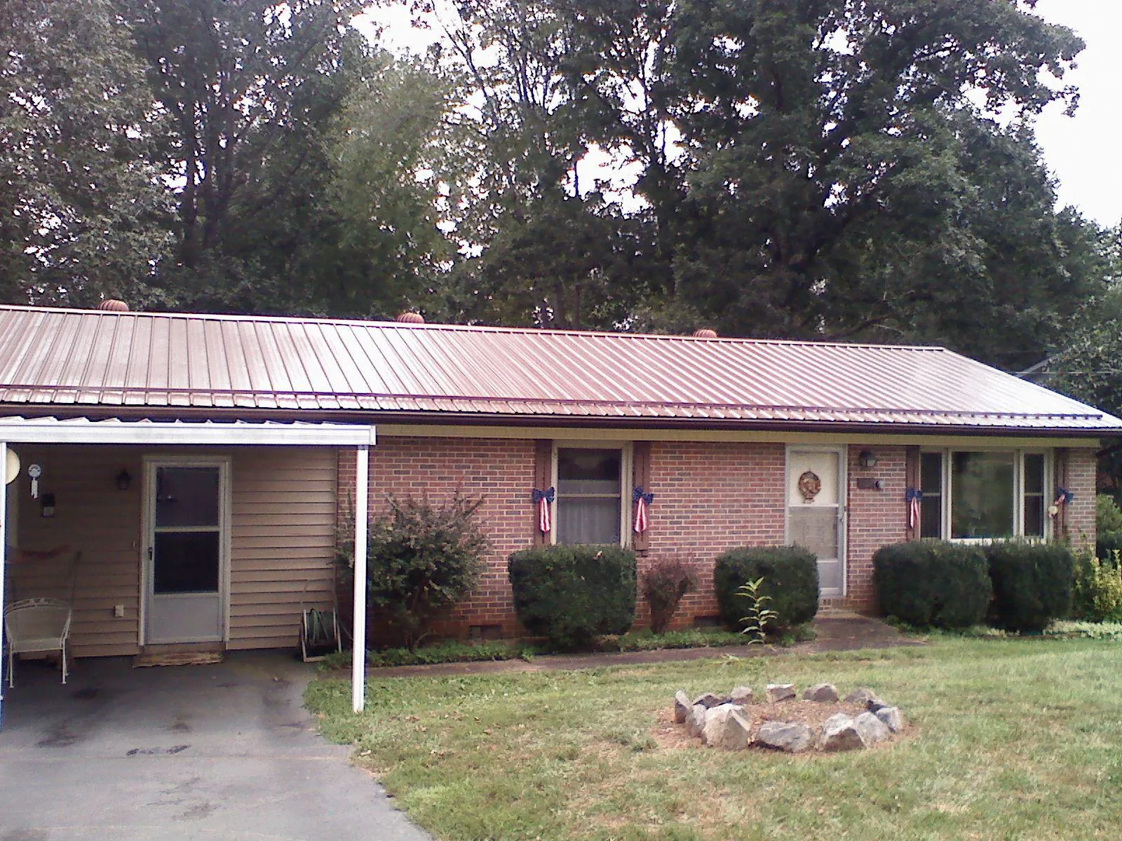Bronze metal roof and carport on a brick ranch home — Roof Repair work by our crew in Platte Center