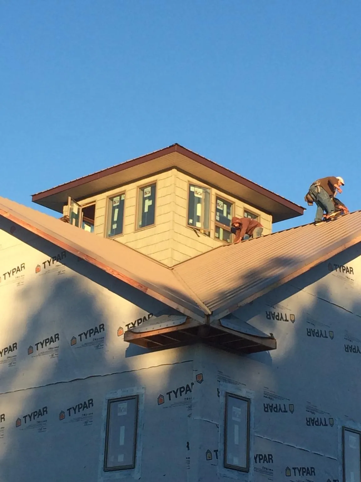 Roofers working around a rooftop cupola on a new metal roof at sunset — Roof Waterproofing in Platte Center by Roofing Brothers
